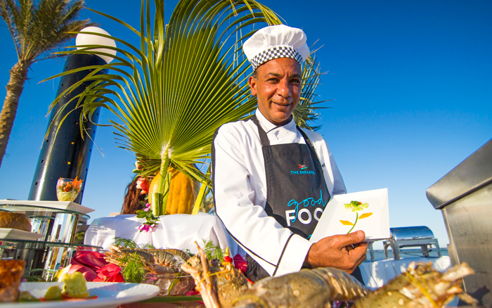 Chef at The Breakers Somabay presenting freshly prepared seafood under the open sky.